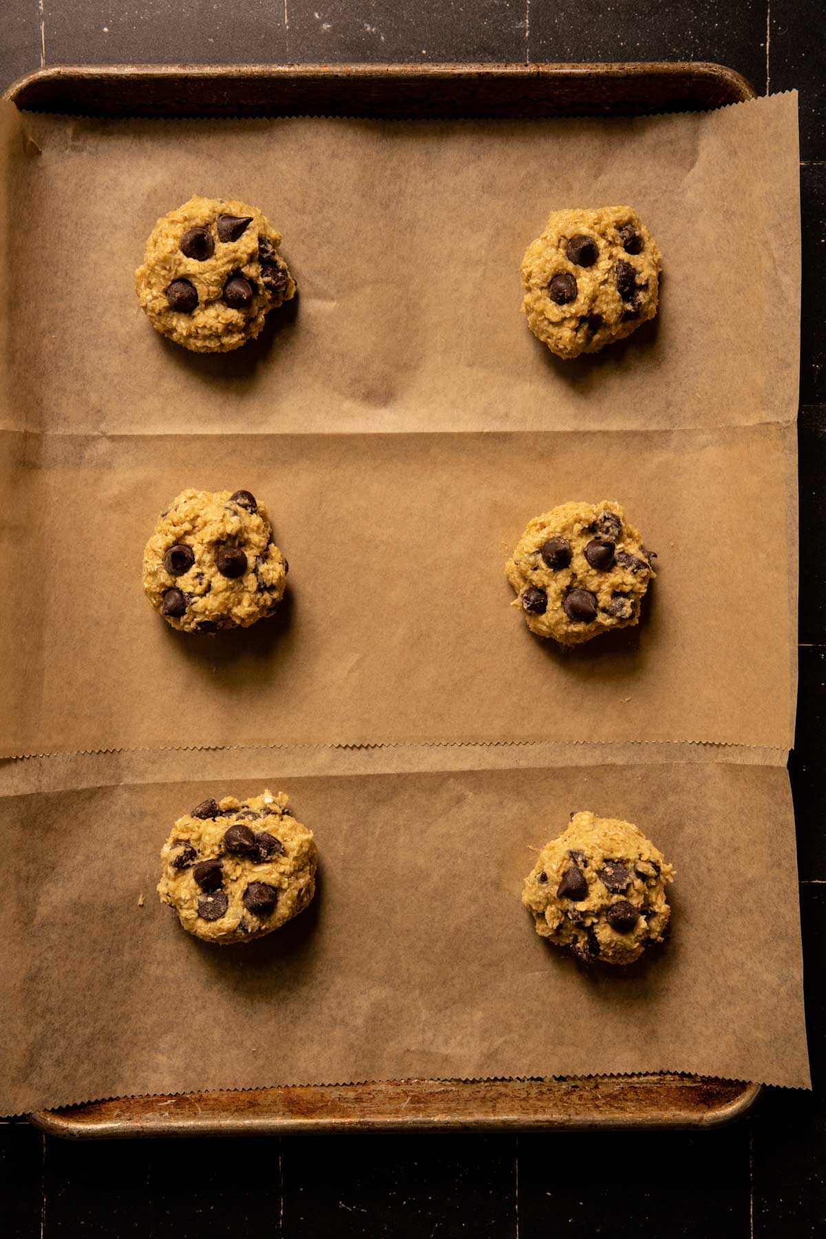 Scoops of oatmeal chocolate chip cookie dough on a sheet pan
