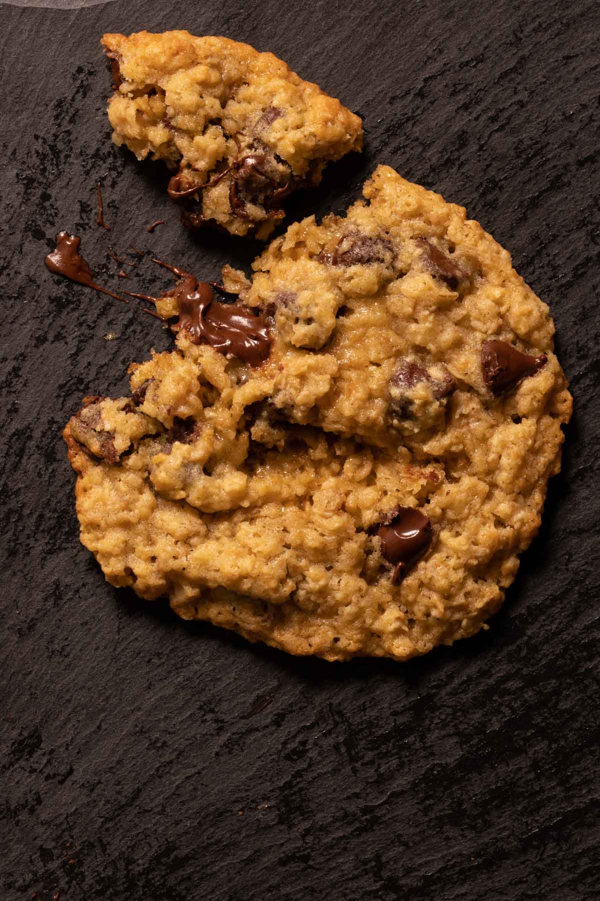 An oatmeal chocolate chip cookie with a bite taken out of it
