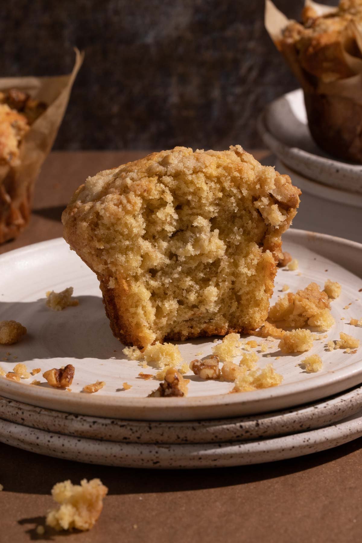 A banana walnut muffin cut in half with crumbs