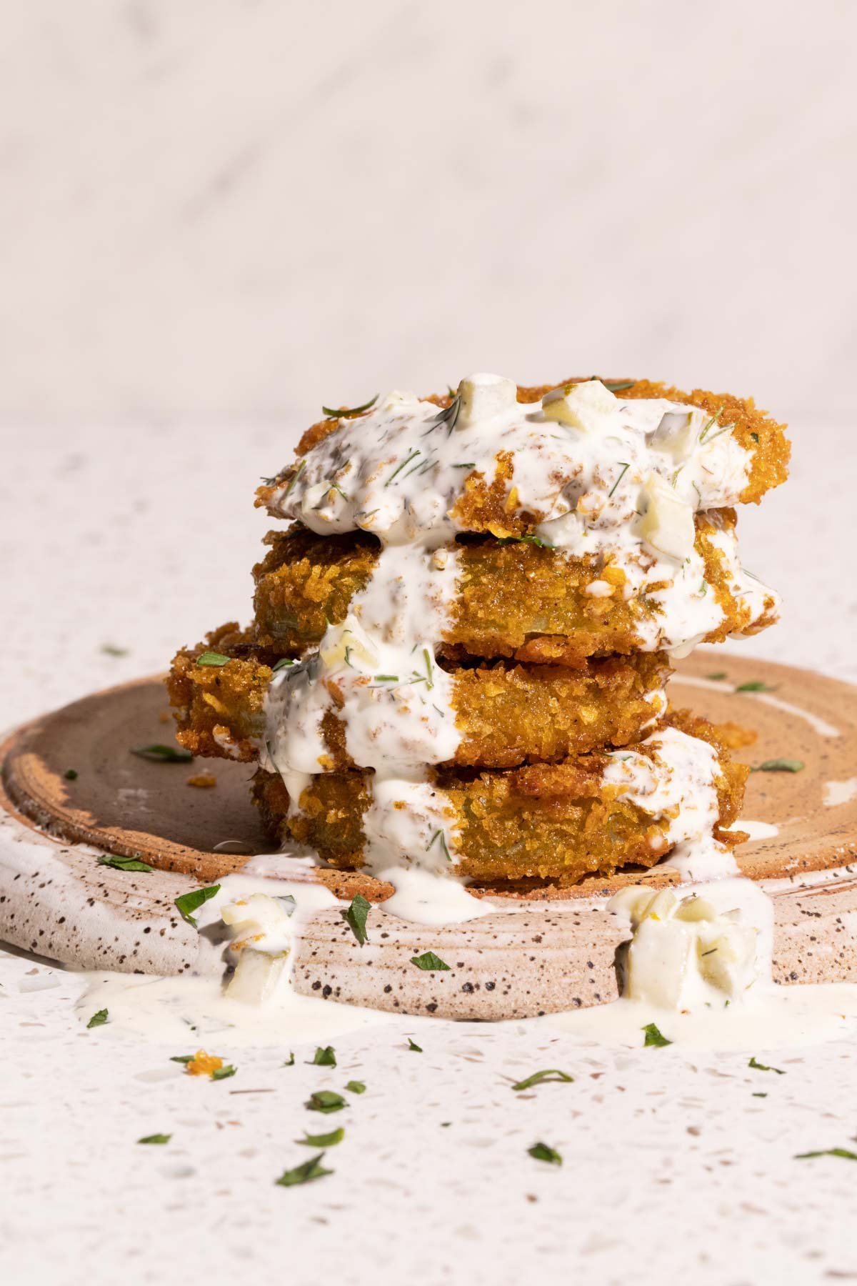 Fried green tomatoes on a plate with dill pickle ranch poured over