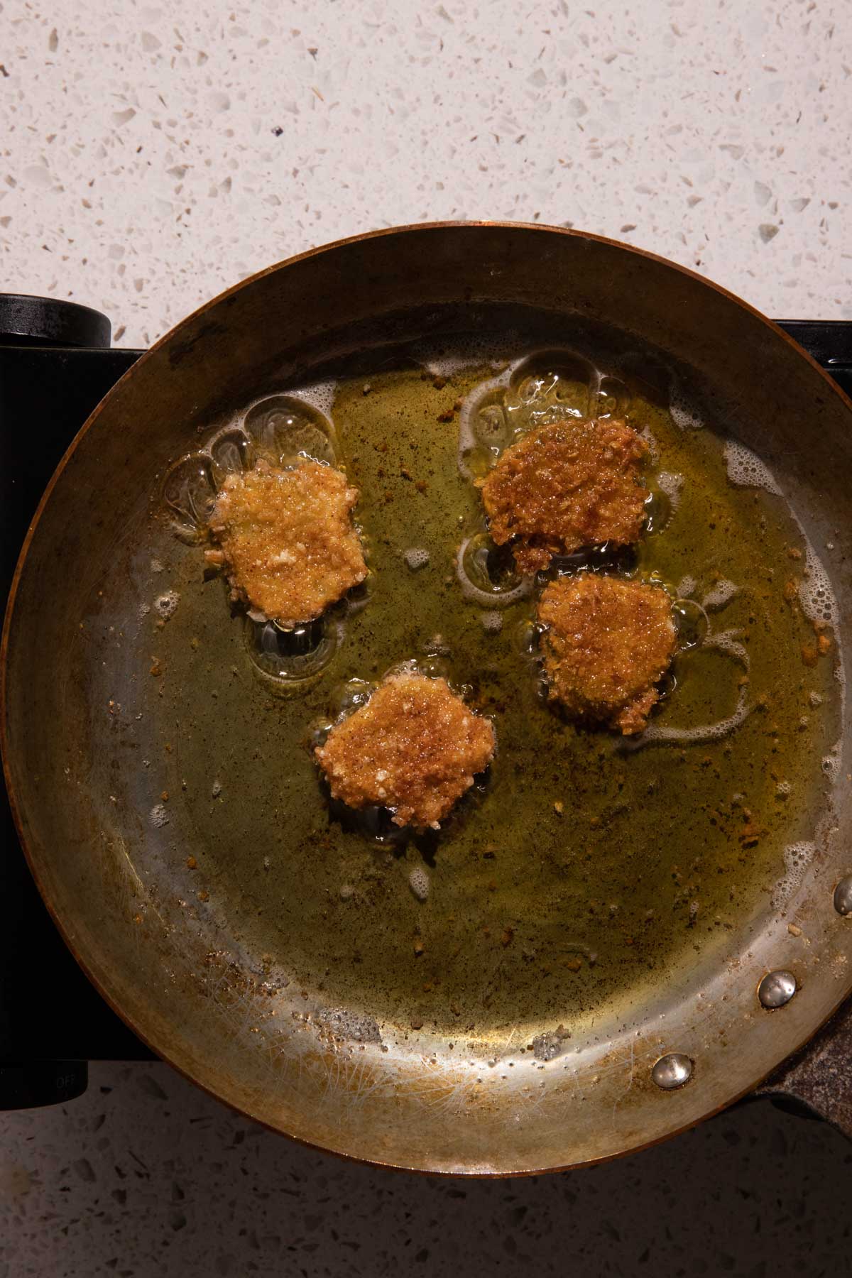 Fried pickles frying in a pan with oil