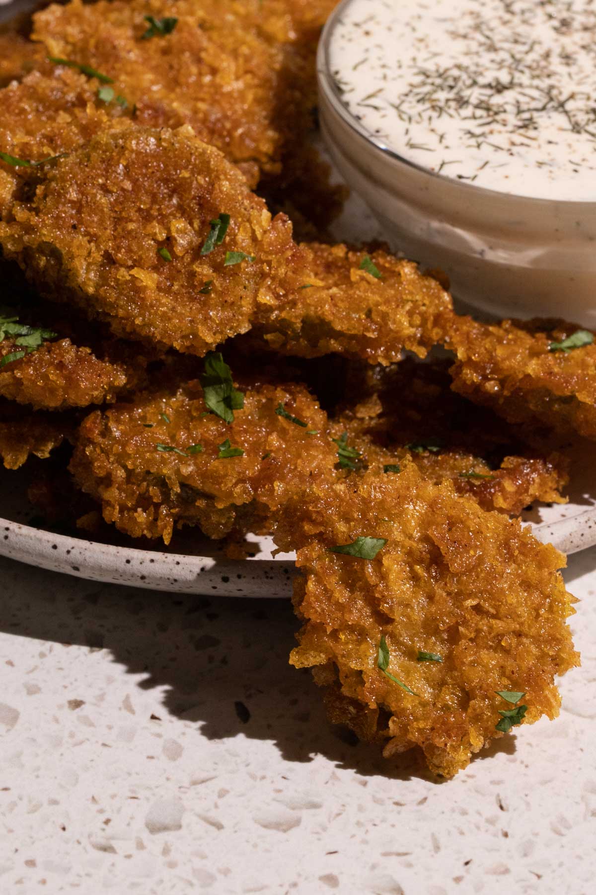 Fried pickles stacked  on a plate with dill pickle ranch dressing