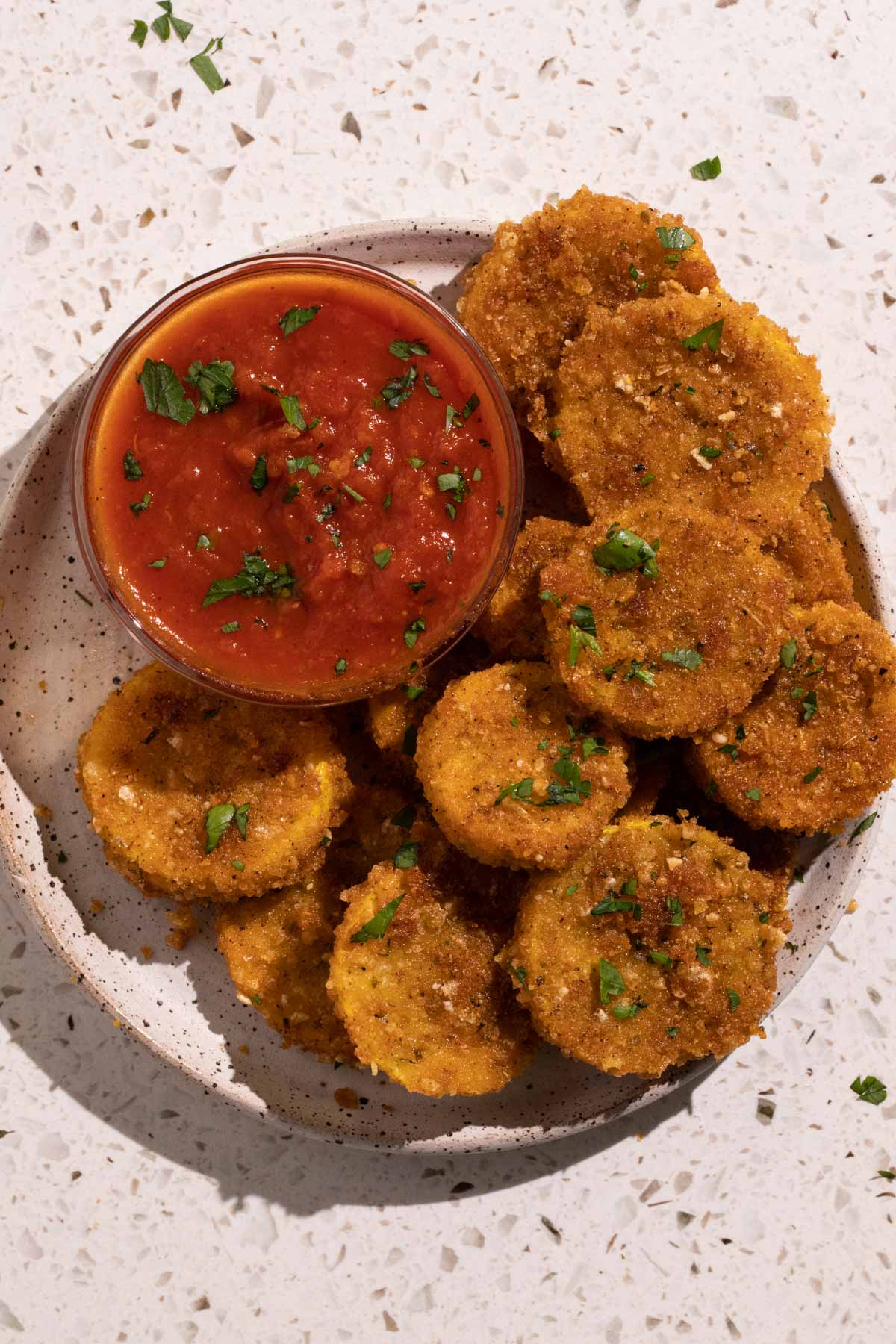 A plate of fried squash with a bowl of marinara