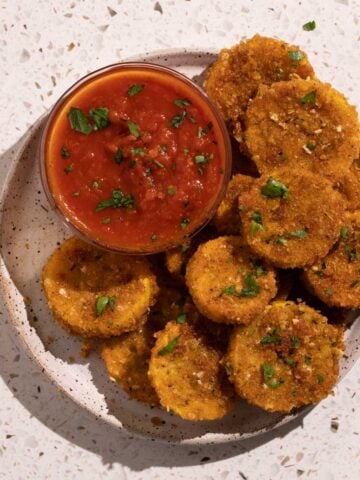 A bowl of marinara and a plate of fried squash