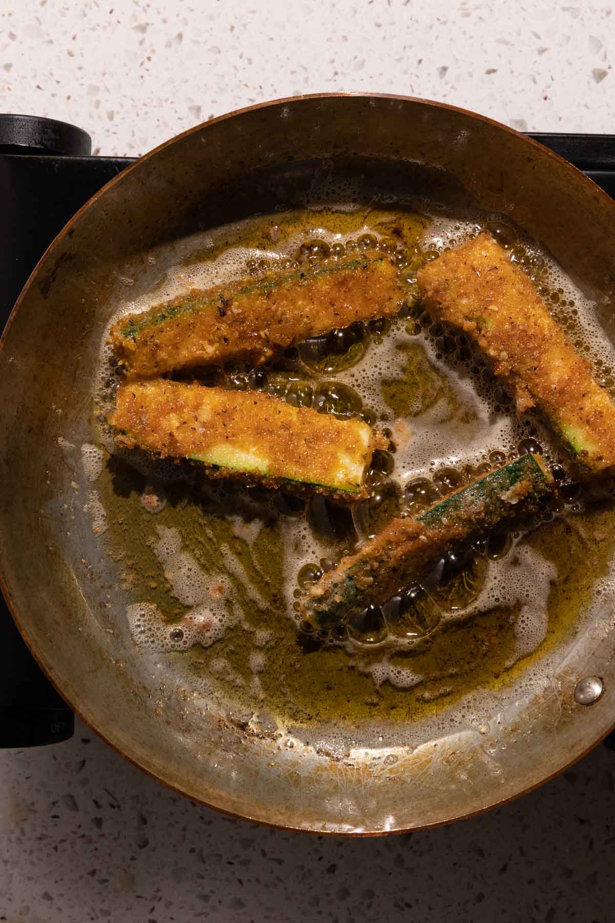 Zucchini sticks frying in a pan