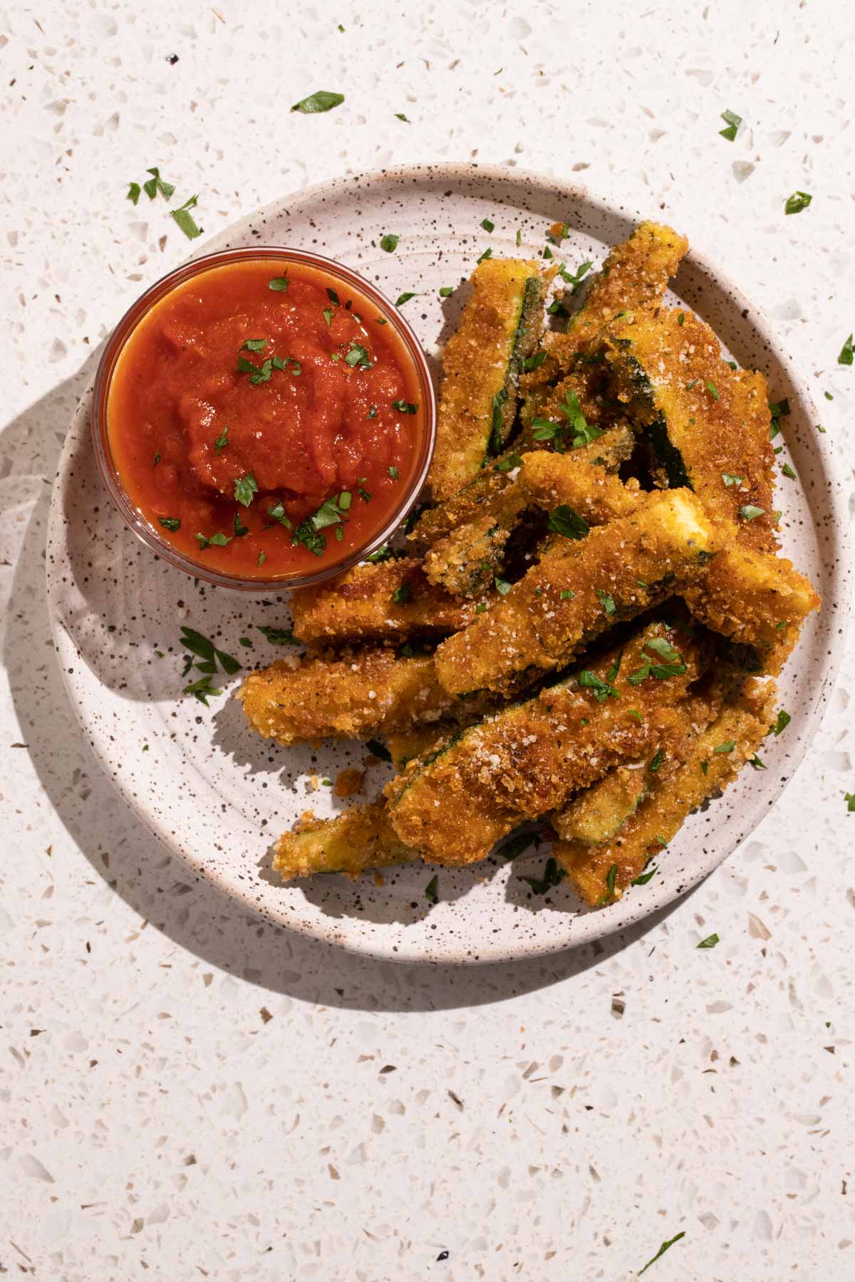 Fried zucchini sticks with marinara sauce on a plate