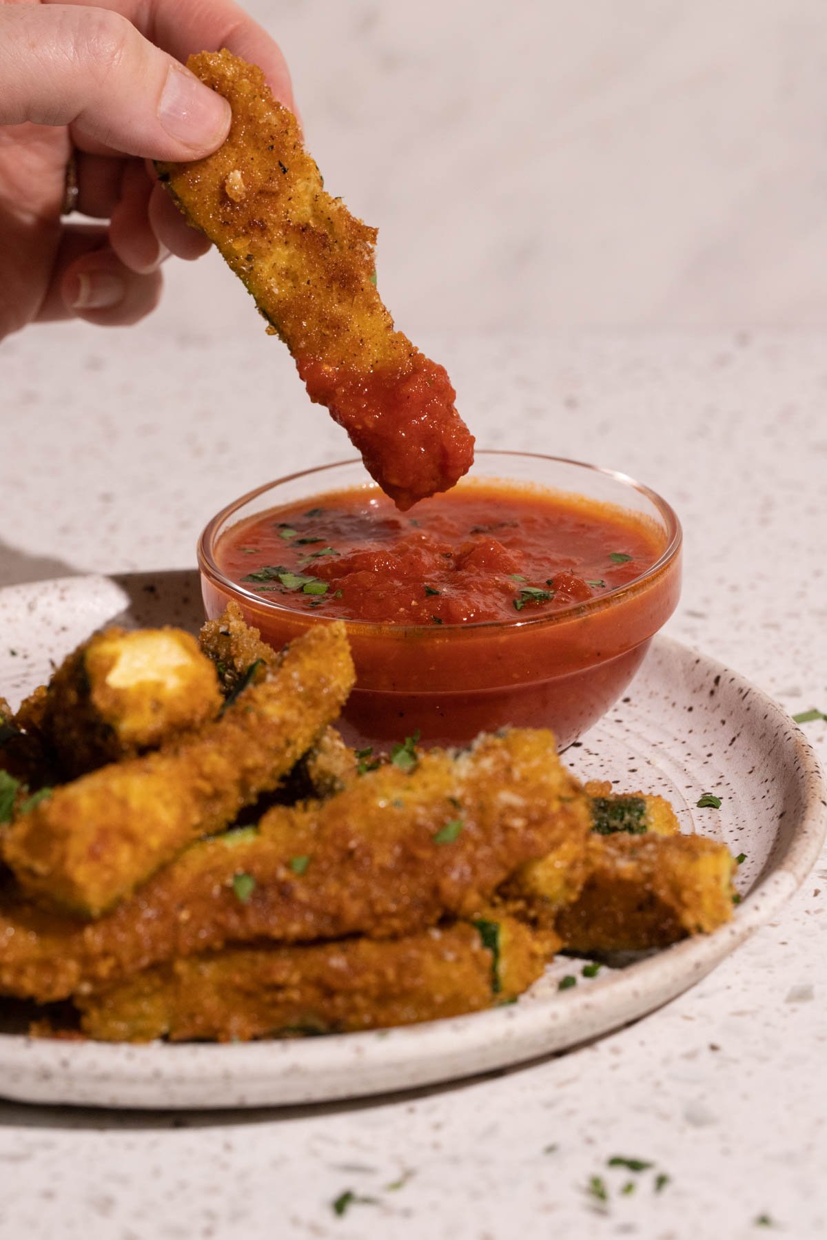 A fried zucchini stick dipped in marinara sauce