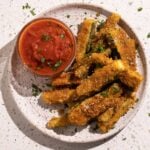 Fried zucchini sticks on a plate with marinara sauce