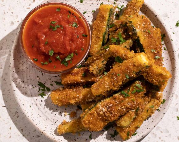 Fried zucchini sticks on a plate with marinara sauce